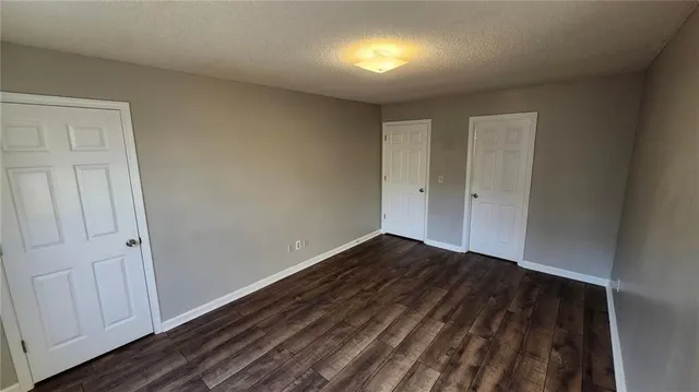 a view of an empty room with wooden floor and closet