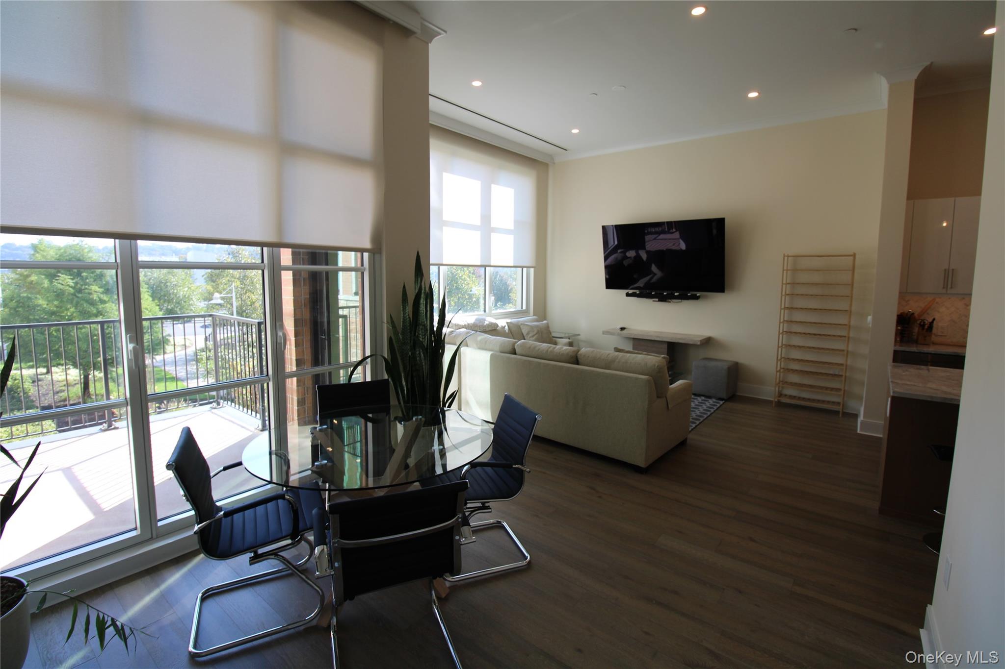 100 Garvies Point Road, Unit 1039 Glen Cove, NY 11542 - Photo 8 of 12 a living room with furniture a flat screen tv and a floor to ceiling window