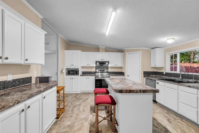 a kitchen with stainless steel appliances granite countertop a stove a sink and white cabinets