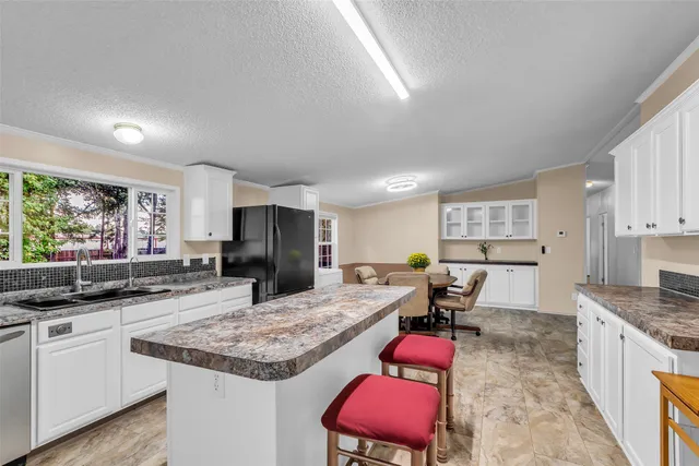 a kitchen with granite countertop kitchen island sink stove and white cabinets