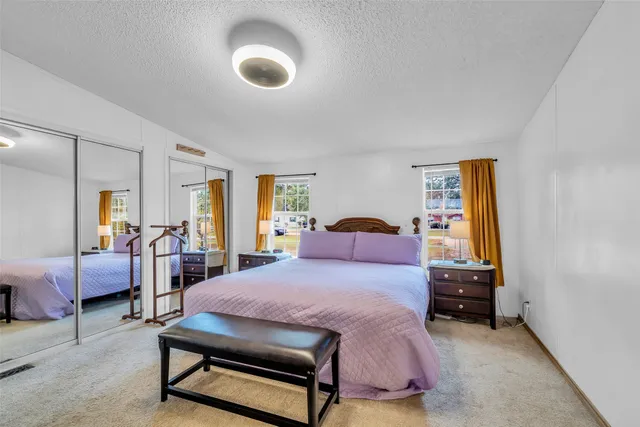 a bedroom with a bed and large windows