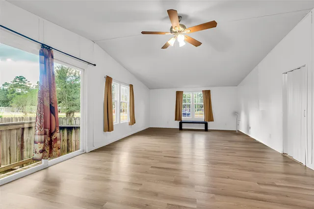 a view of an empty room with a window and wooden floor