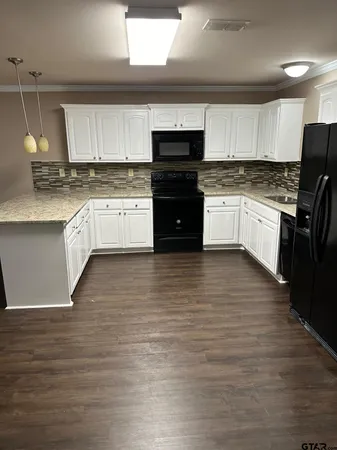 a kitchen with granite countertop a refrigerator stove top oven and cabinets