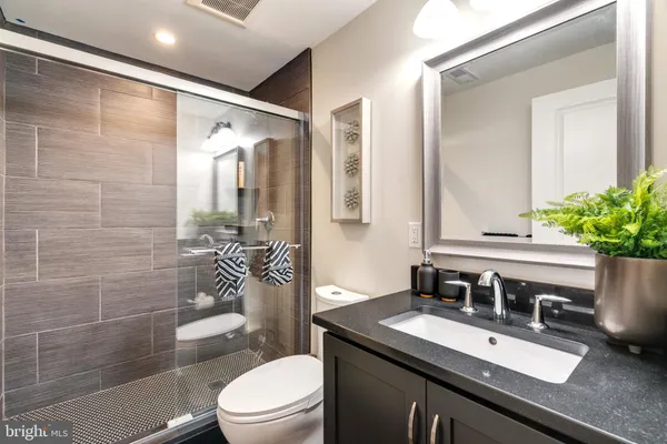 a bathroom with a sink vanity granite toilet and a mirror