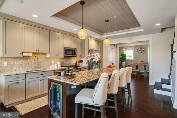 a kitchen with stainless steel appliances granite countertop a stove top oven a sink dishwasher a dining table and chairs with wooden floor