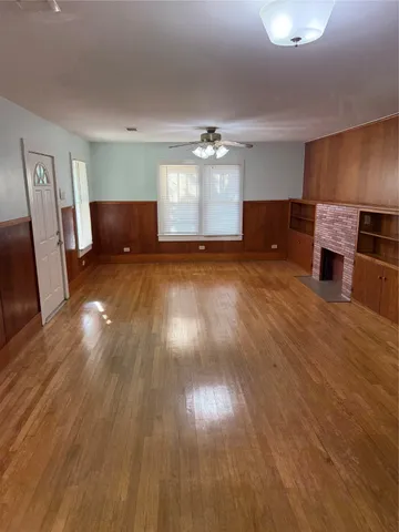 a view of kitchen and empty room with wooden floor