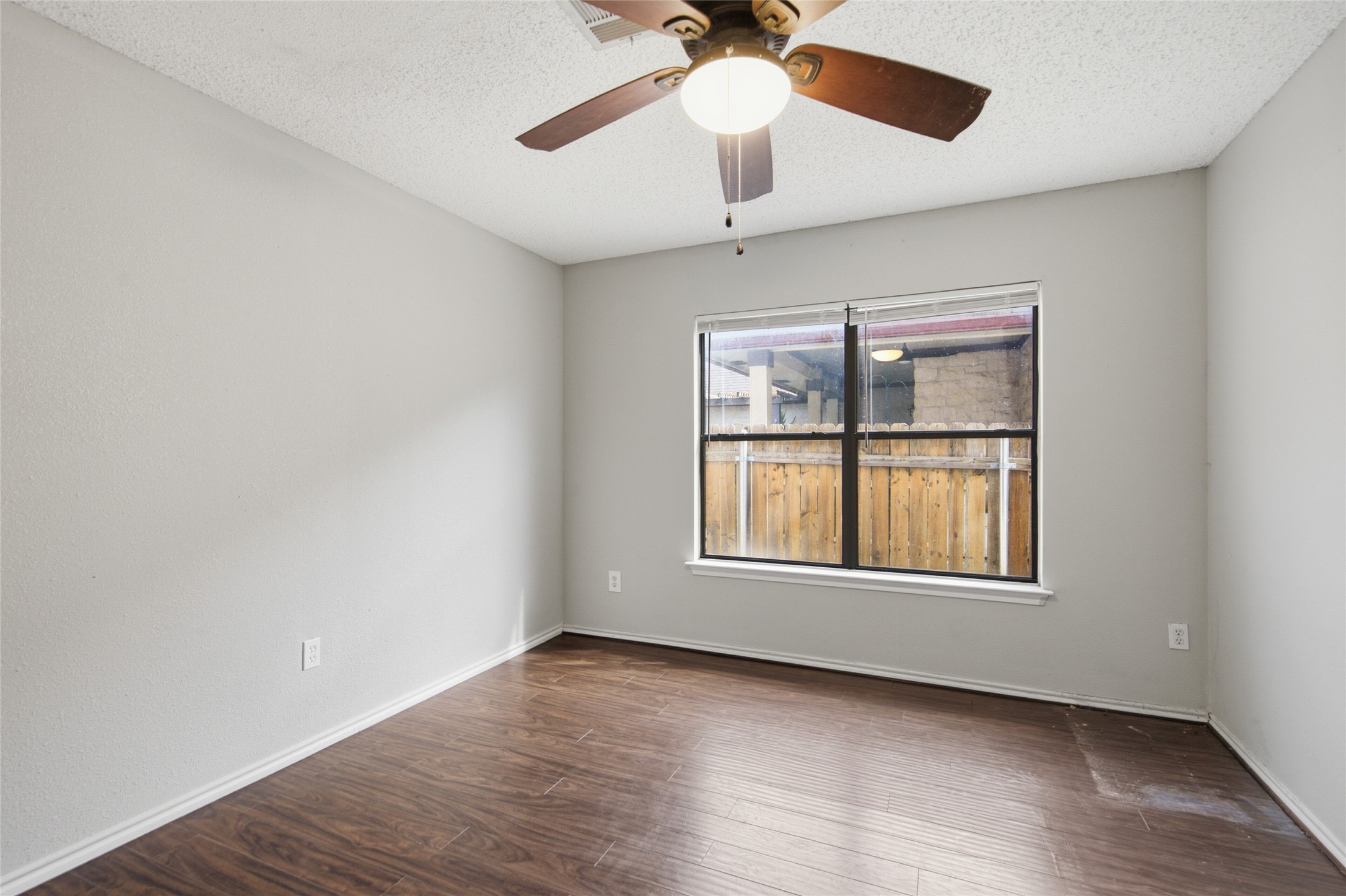 7900 Rosenberry Drive Austin, TX 78747 - Photo 4 of 27 A well-lit bedroom features durable hardwood flooring and a functional ceiling fan with lighting.