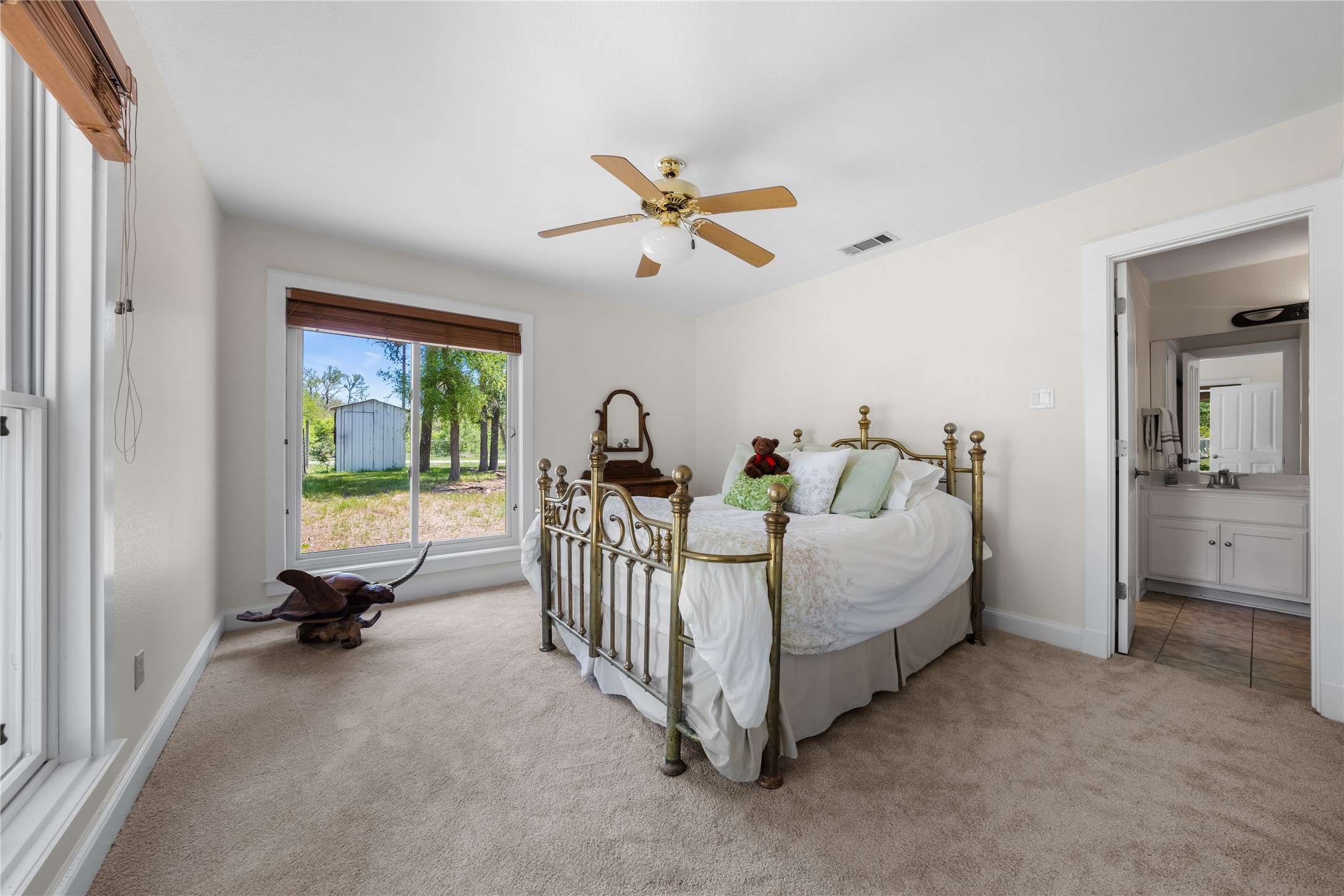 7670 Nez Perce Trace Manor, TX 78653 - Photo 15 of 40 Bedroom with ceiling fan, visible vents, light carpet, a sink, and baseboards