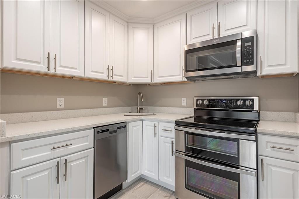 780 10th Avenue South, Unit 23 Naples, FL 34102 - Photo 12 of 15 a kitchen with white cabinets and stainless steel appliances