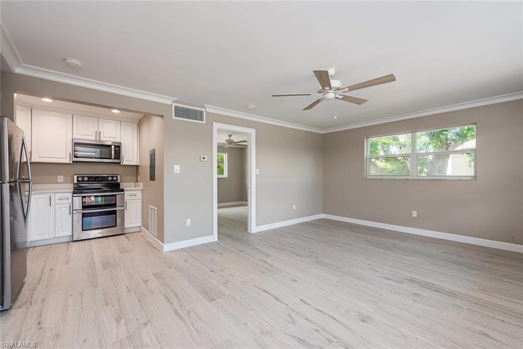 780 10th Avenue South, Unit 23 Naples, FL 34102 - Photo 10 of 15 a view of a kitchen with a stove a ceiling fan and wooden floor