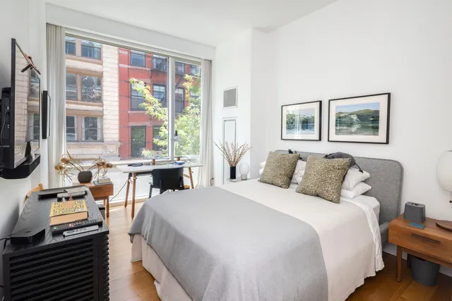 a spacious bedroom with a bed and wooden floor