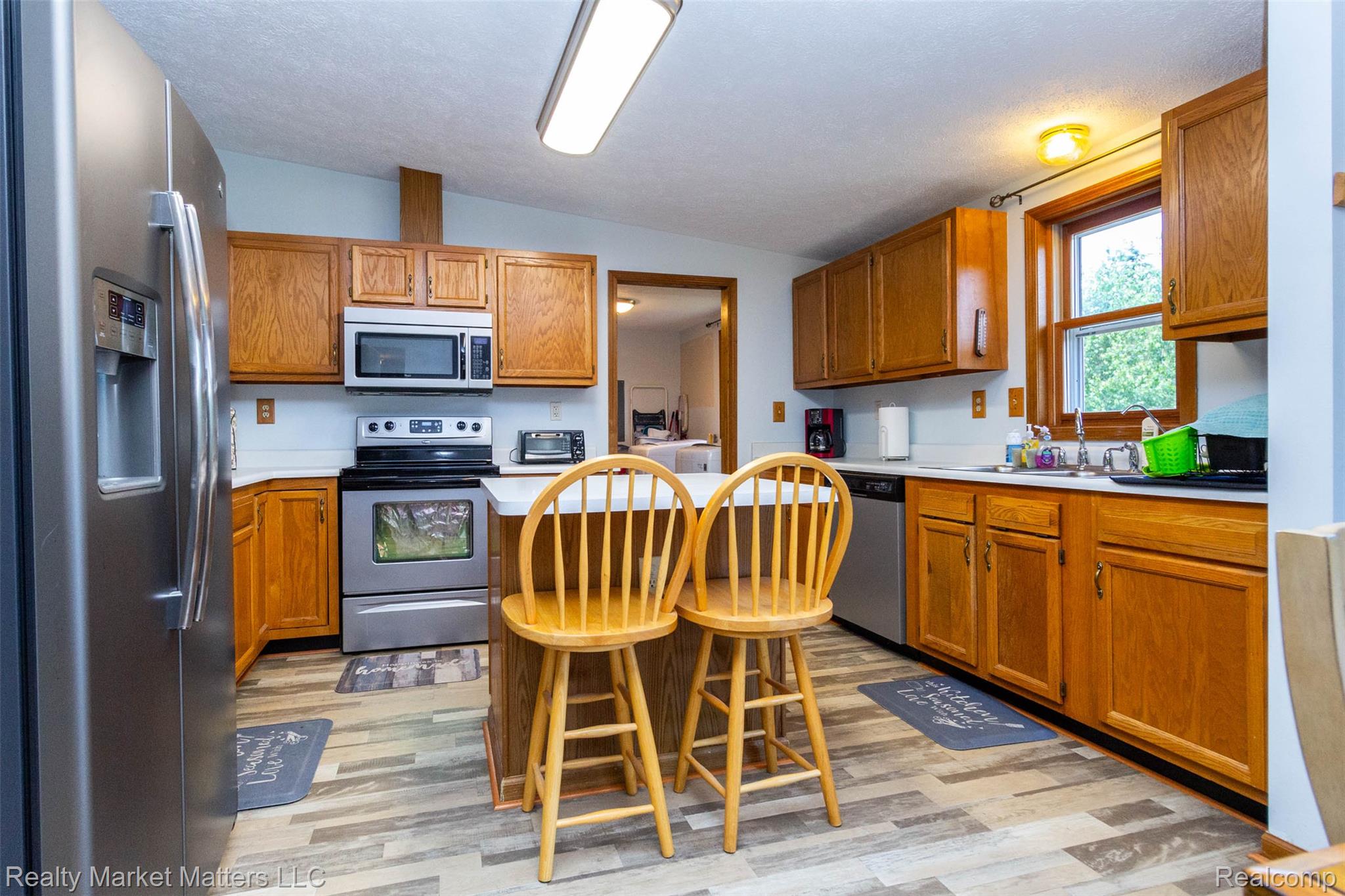 4951 Laur Road North Branch, MI 48461 - Photo 8 of 34 Kitchen featuring wood-finish cabinetry, stainless steel appliances, a center island with countertop seating, and wood-finish flooring