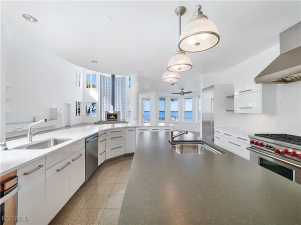 a large white kitchen with a large window a sink and stainless steel appliances