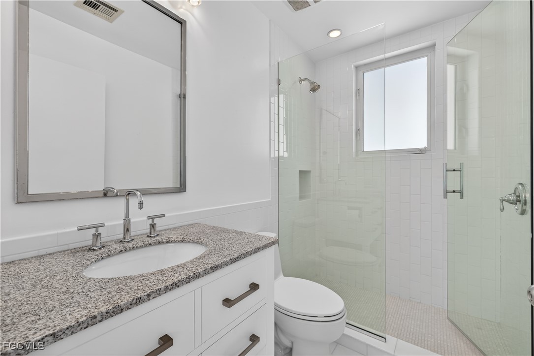3402 West Riverside Drive Fort Myers, FL 33901 - Photo 35 of 50 a bathroom with a granite countertop sink a toilet and a mirror