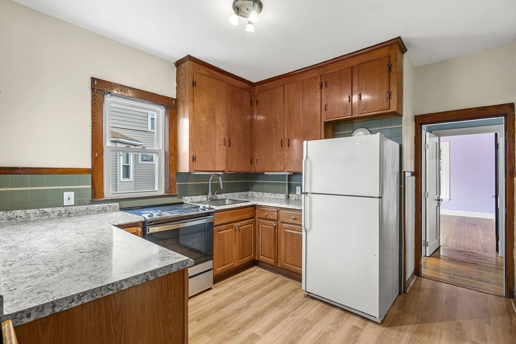 76 Myrtle Street Lynn, MA 01905 - Photo 7 of 27 a kitchen with a refrigerator a sink and cabinets