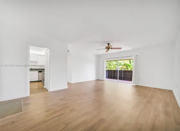 a view of an empty room with a window and wooden floor
