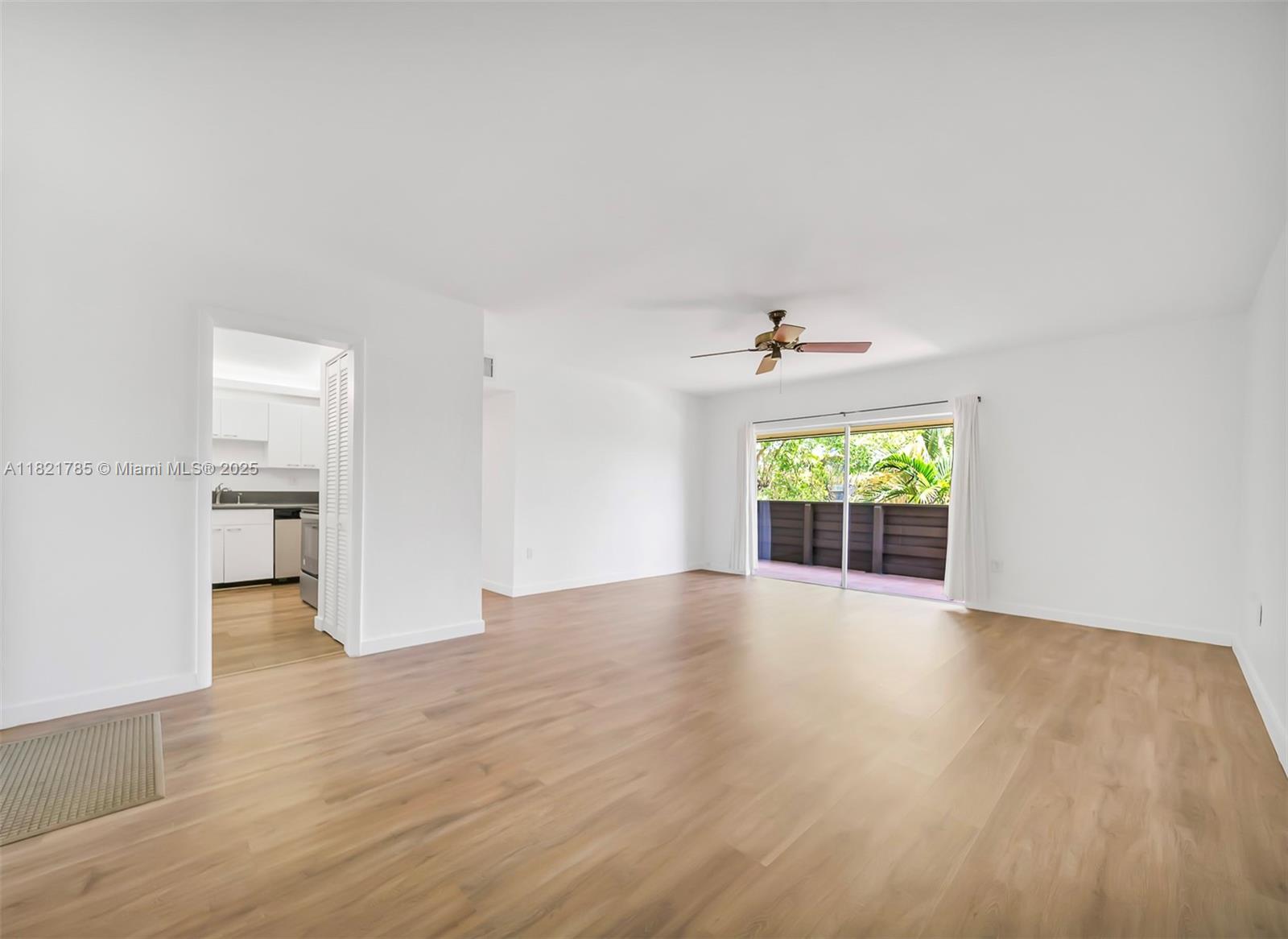 a view of an empty room with a window and wooden floor