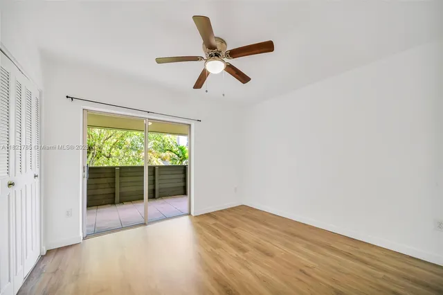 a view of empty room with wooden floor and fan