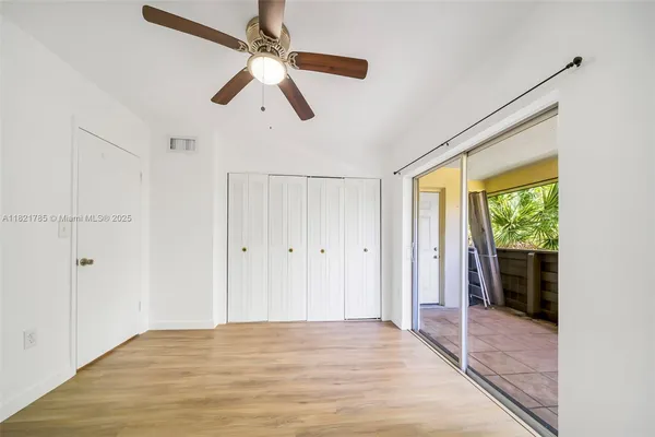 a view of empty room with wooden floor and fan