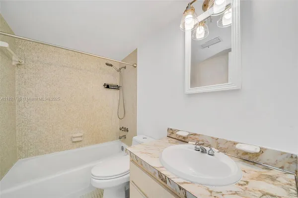 a bathroom with a bathtub shower sink vanity and toilet