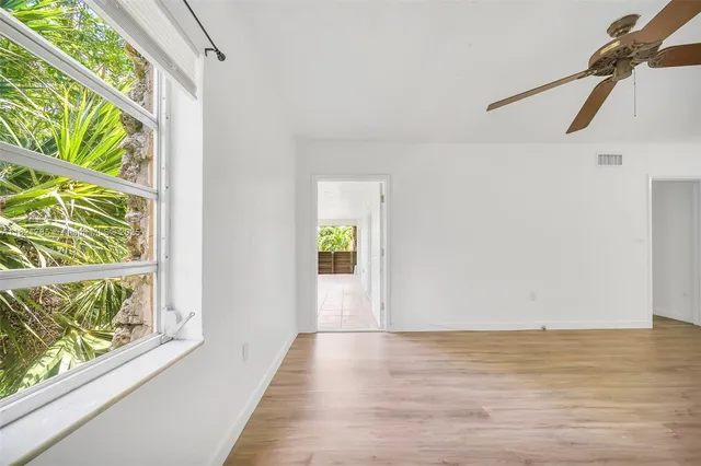 a view of an empty room with wooden floor and windows