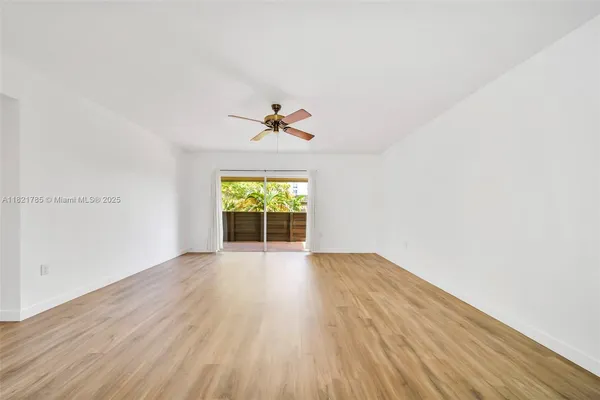 an empty room with wooden floor chandelier fan and windows