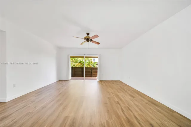 an empty room with wooden floor chandelier fan and windows