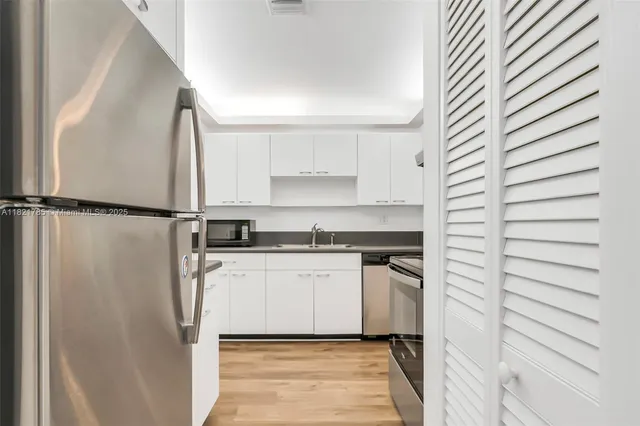 a kitchen with a refrigerator and white cabinets
