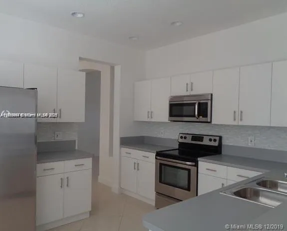 a kitchen with white cabinets and black appliances
