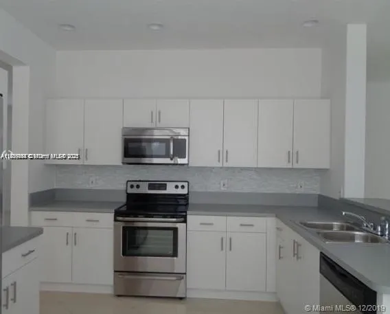 a kitchen with white cabinets and stainless steel appliances