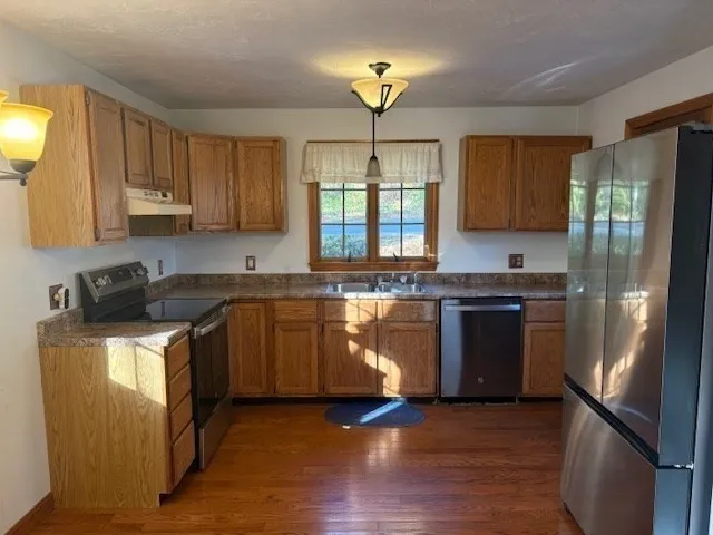 a kitchen with granite countertop wooden floors stainless steel appliances a sink and a window