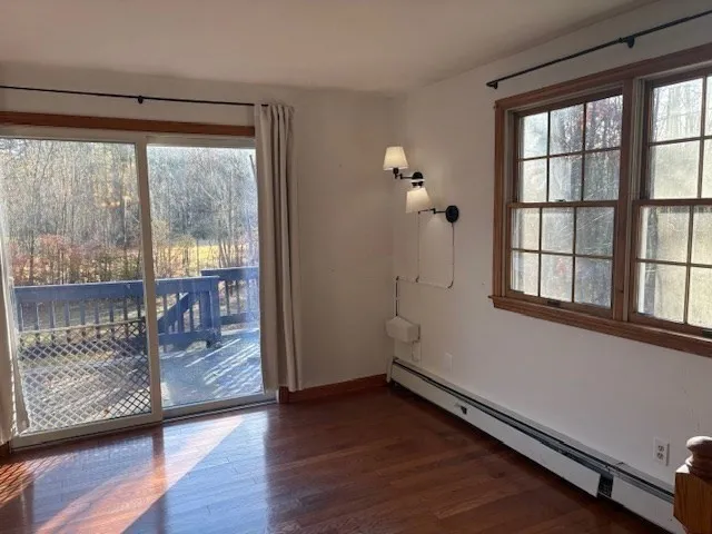 an empty room with wooden floor and windows