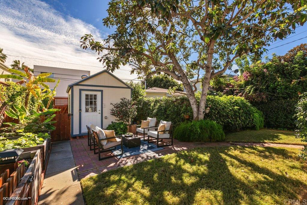 1453-1455 Thomas Avenue San Diego, CA 92109 - Photo 21 of 37 a view of a patio with table and chairs potted plants and a large tree