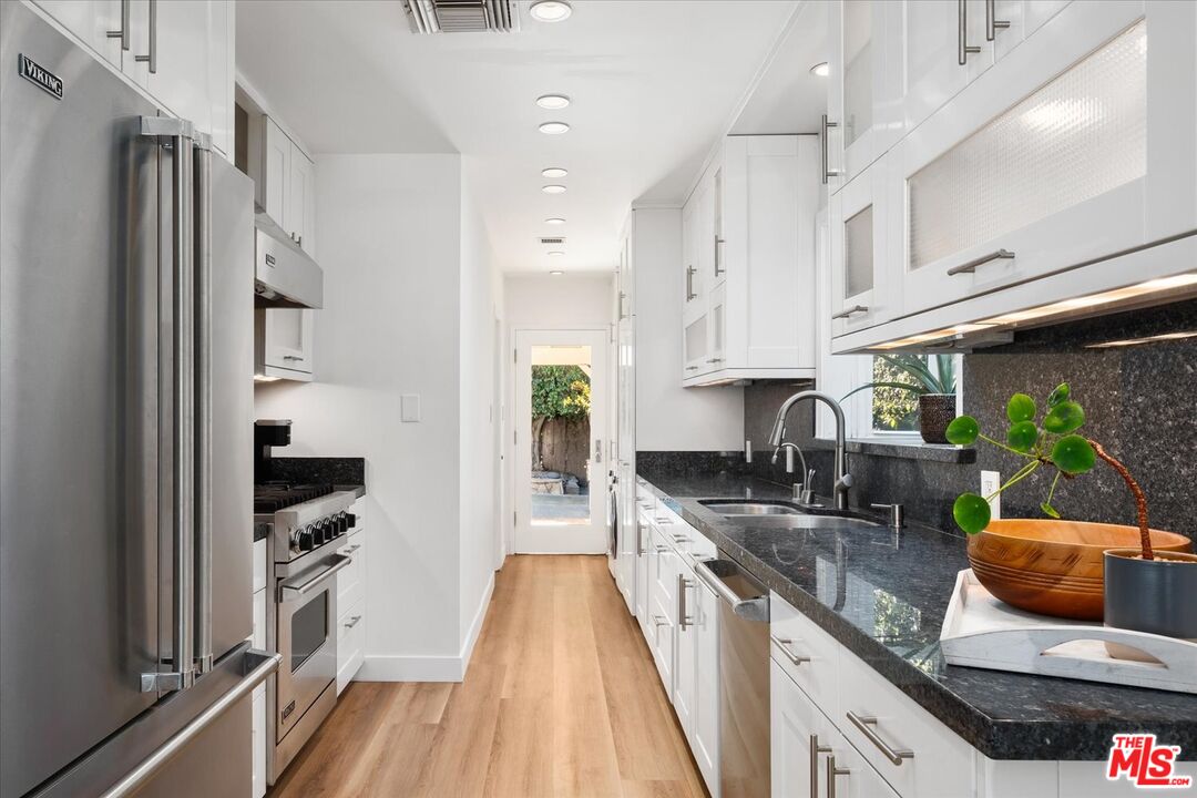 10944 Stever Street Culver City, CA 90230 - Photo 9 of 25 a kitchen with stainless steel appliances granite countertop a refrigerator a stove and a sink with wooden floor
