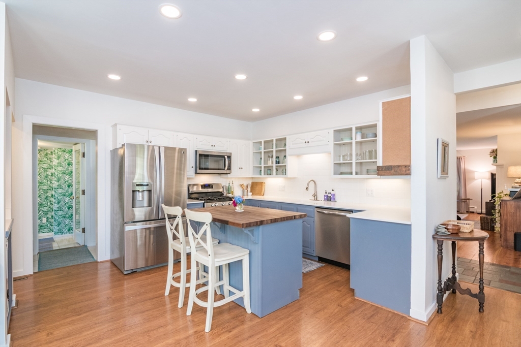 116 High Street Amherst, MA 01002 - Photo 11 of 42 a kitchen with stainless steel appliances kitchen island granite countertop wooden floor and refrigerator