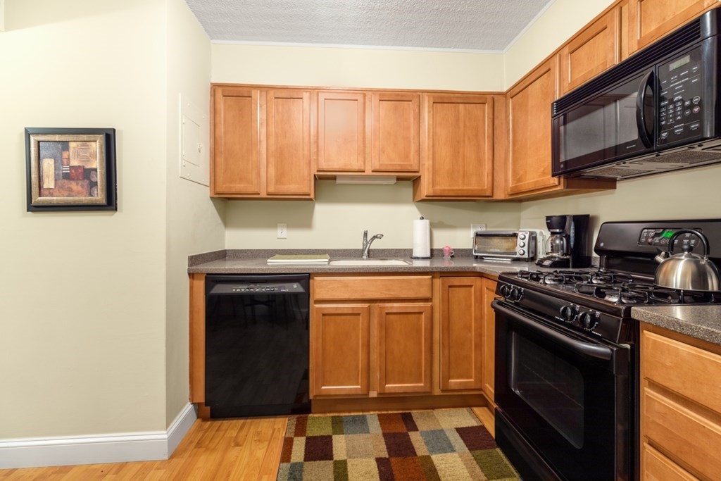 1500 Worcester Road, Unit 321 Framingham, MA 01702 - Photo 20 of 42 a kitchen with stainless steel appliances granite countertop a stove a sink and a microwave