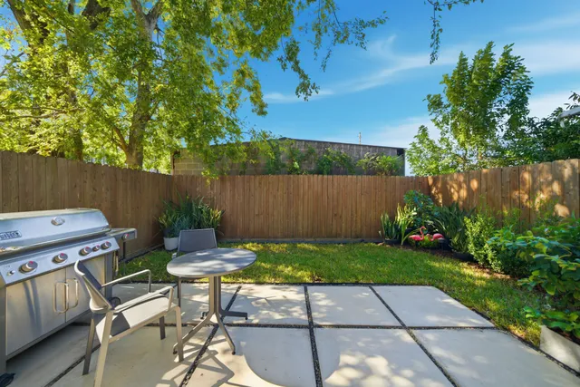 a view of a patio with table and chairs and potted plants with wooden fence