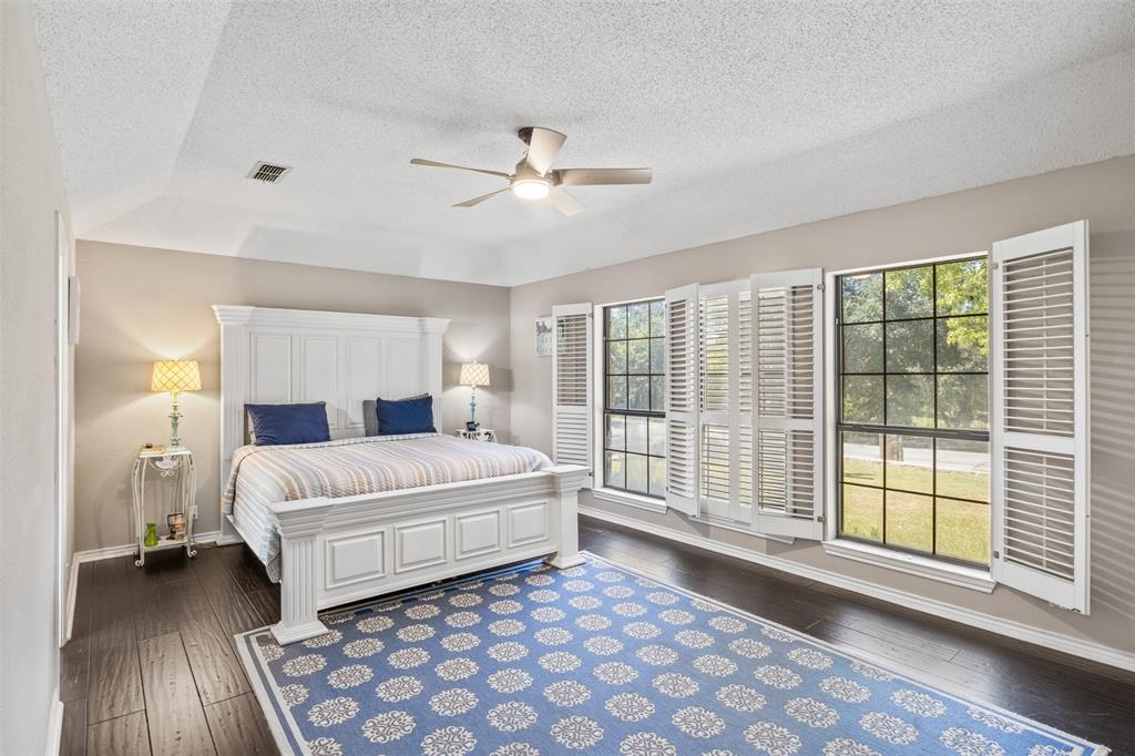 8919 Bontura Road Granbury, TX 76049 - Photo 21 of 35 a spacious bedroom with a large bed and a chandelier