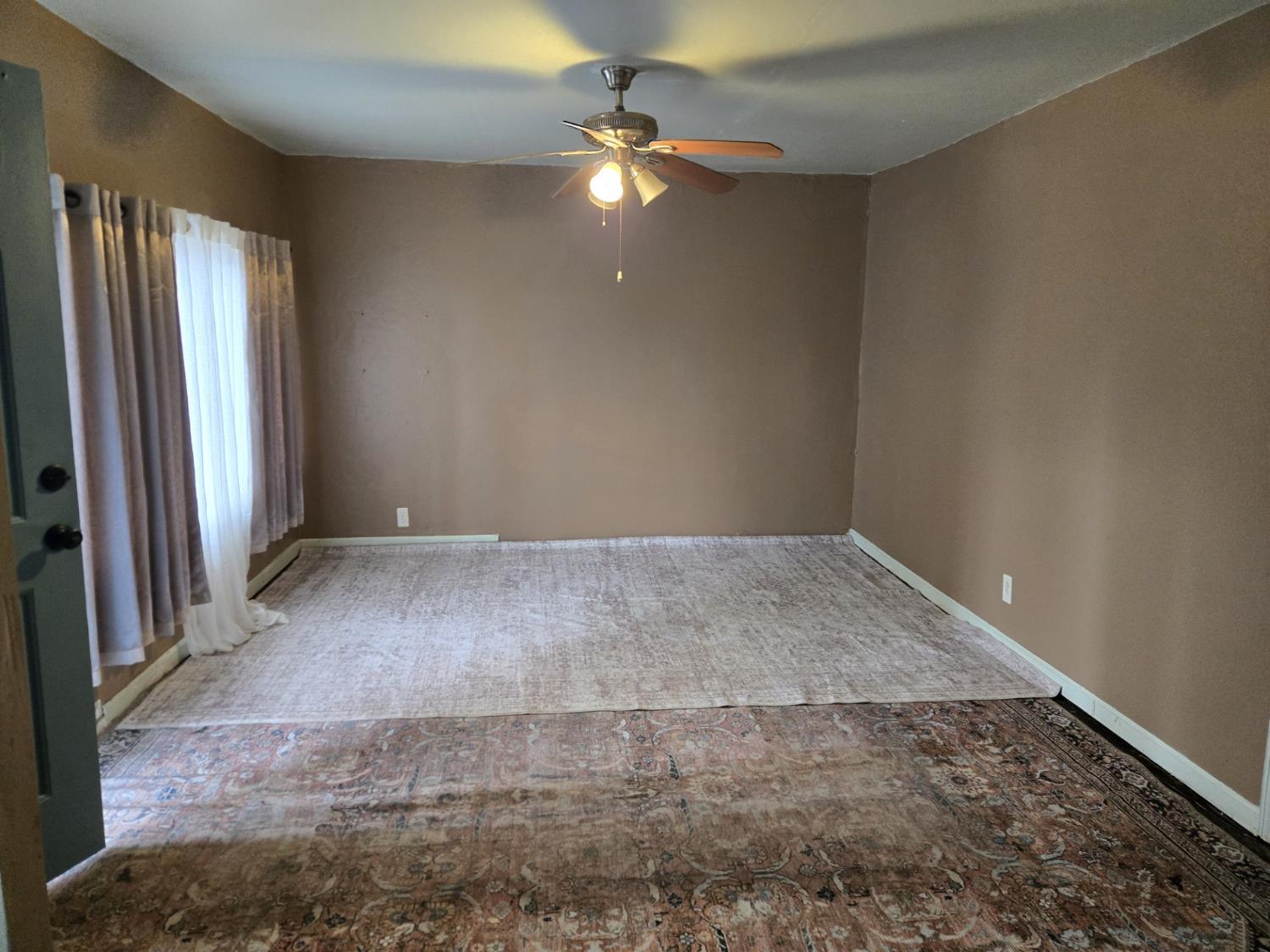 1726 Merced Street Dos Palos, CA 93620 - Photo 3 of 12 an empty room with a ceiling fan and window