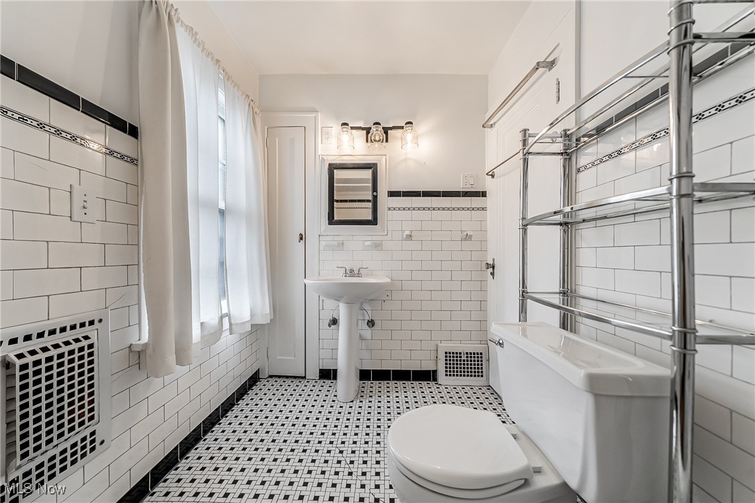 11703 Granger Road Cleveland, OH 44125 - Photo 15 of 41 Full Bathroom featuring tile walls, light tile patterned flooring, and wainscoting