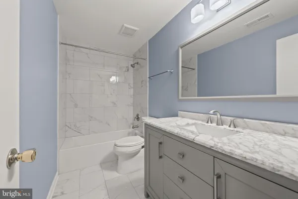 a bathroom with a granite countertop sink a toilet and shower