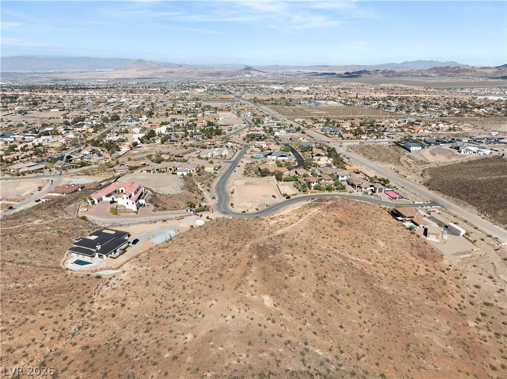 Perched atop a hill, this expansive desert landscape reveals an intricate network of residential roads leading to scattered homes, all under an azure sky.