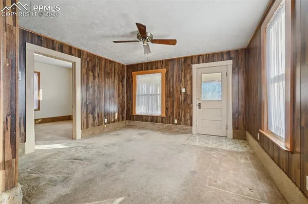 an empty room with ceiling fan and windows