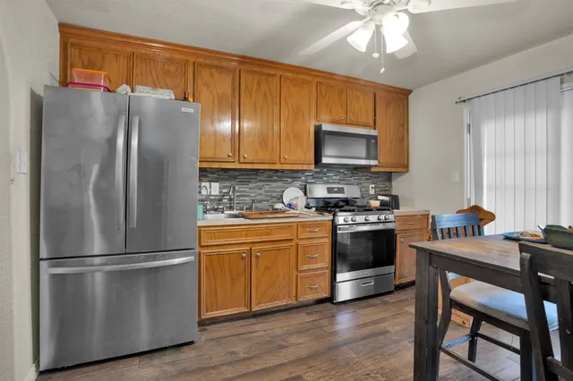 a kitchen with stainless steel appliances granite countertop a refrigerator a stove a sink a dining table and chairs