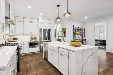 a kitchen with stainless steel appliances kitchen island granite countertop a refrigerator a stove and white cabinets