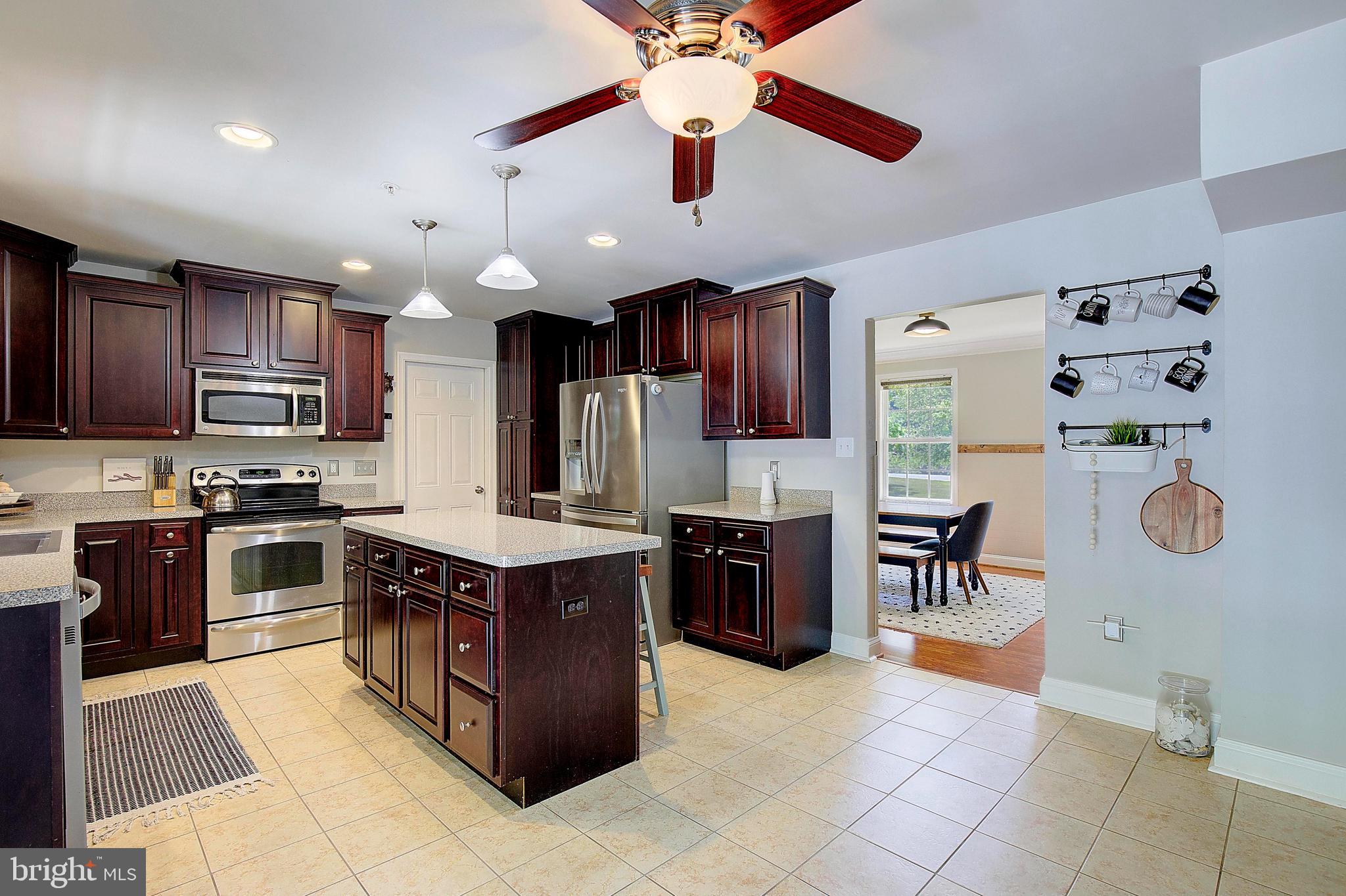 7006 Prout Road Friendship, MD 20758 - Photo 6 of 48 a kitchen with stainless steel appliances granite countertop a stove top oven a refrigerator a sink dishwasher with a dining table and chairs