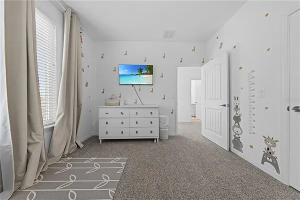 a bedroom with a large bed and a flat tv screen on dresser