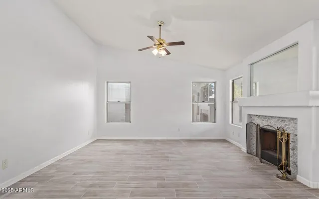 an empty room with windows and fireplace