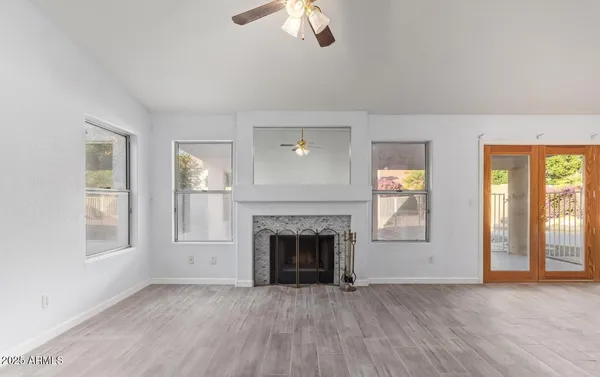 an empty room with windows fireplace and wooden floor