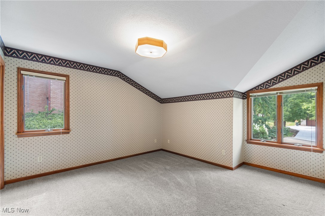 2317 Raintree Street Northeast Canton, OH 44705 - Photo 21 of 40 Additional living space with plenty of natural light, vaulted ceiling, wallpapered walls, carpet floors, and a textured ceiling